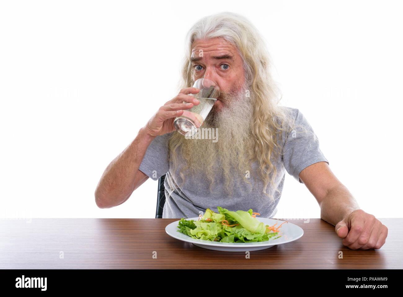 Studio shot of senior bearded man drinking glass of water with p Stock Photo