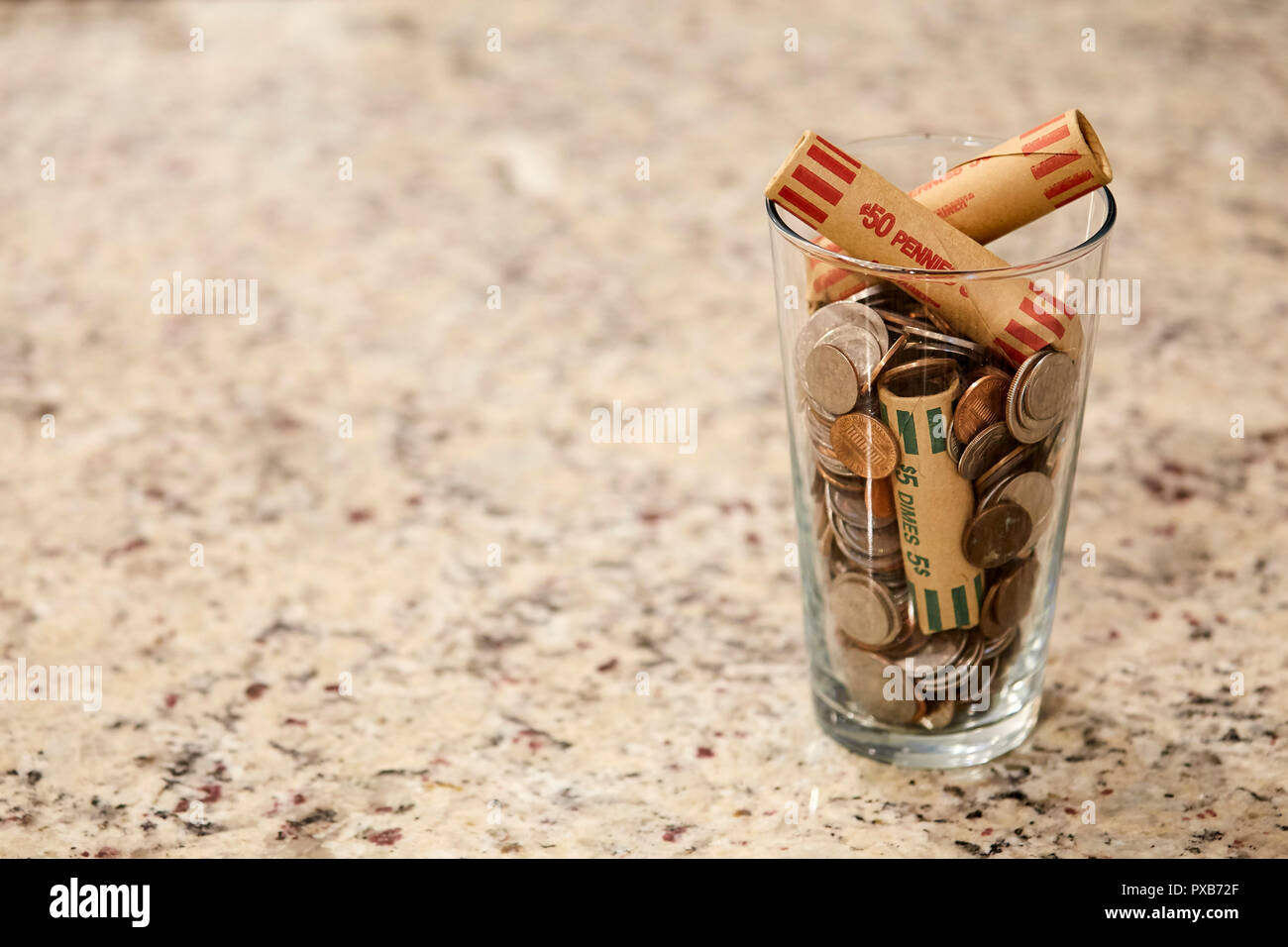 Glass jar of coins in cup on desk money savings debt bank rich poor