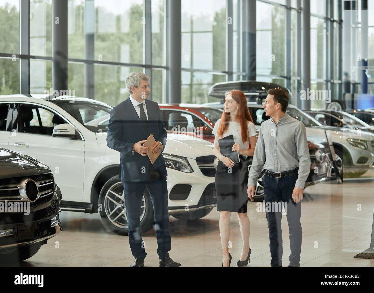 Car sales manager telling about the features of the car to the customers at the dealership Stock