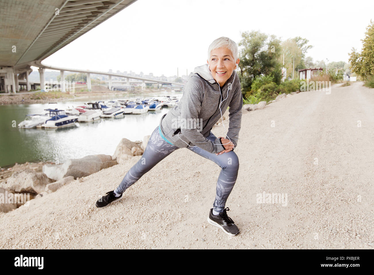 Senior Woman Exercise And Listening Music With Earphones Gray