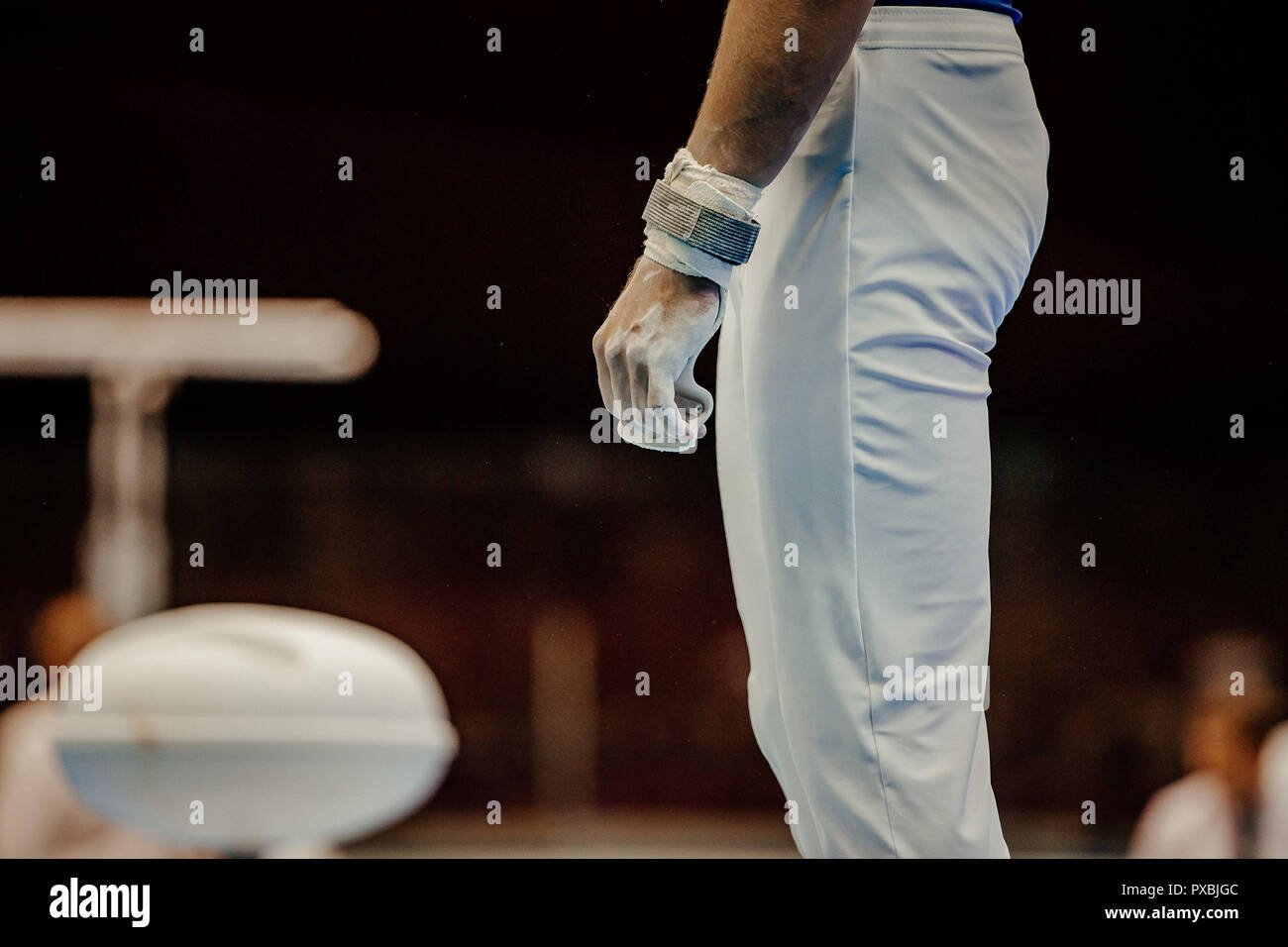 gymnast hand grips in gym chalk before performing on horizontal bar