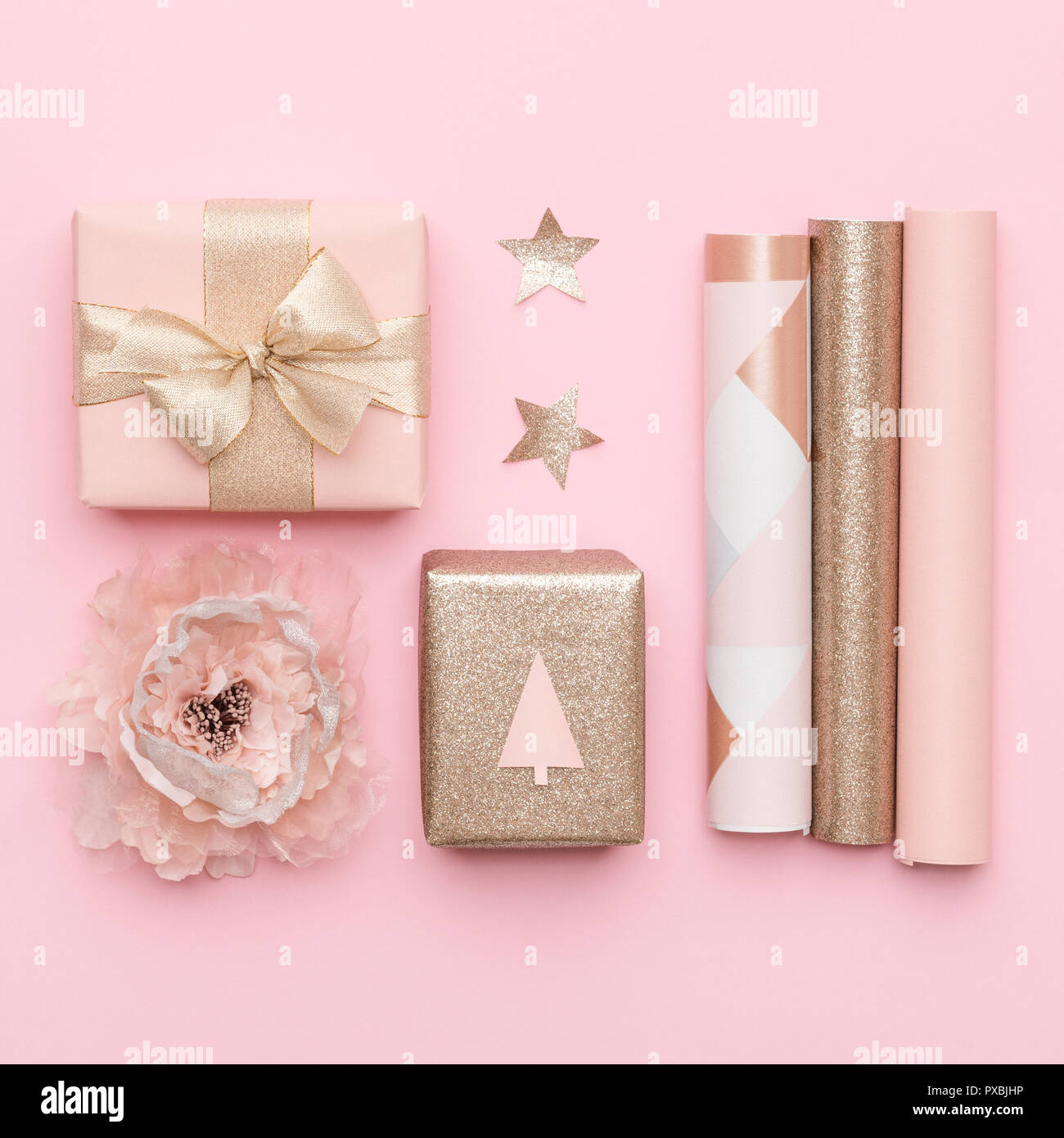 Gift wrapping. Pink and gold nordic christmas gifts isolated on pastel pink background. Wrapped xmas boxes. Stock Photo