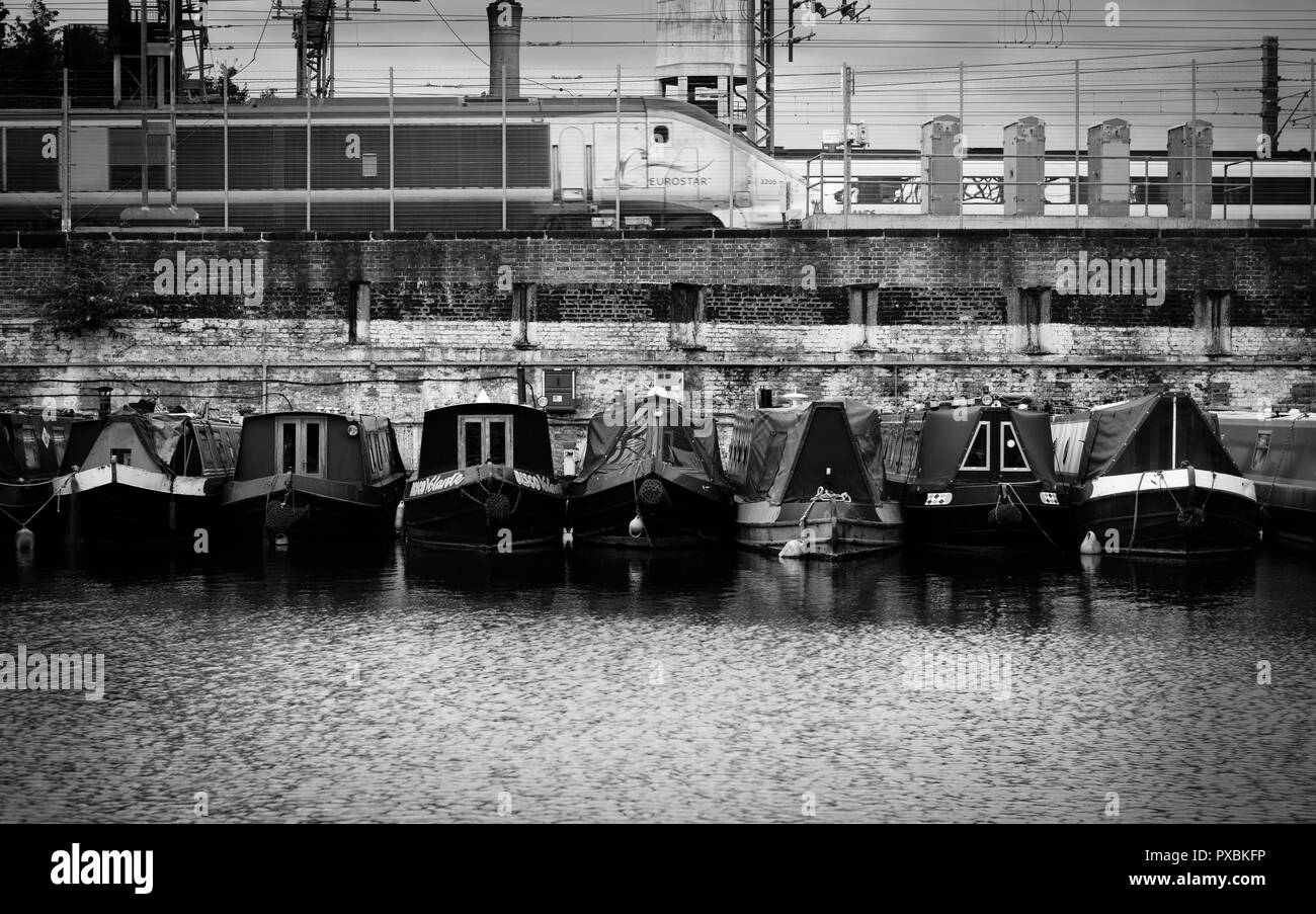 A Eurostar train passes canal boats moored in the Regent's Canal, King's Cross, London. Stock Photo