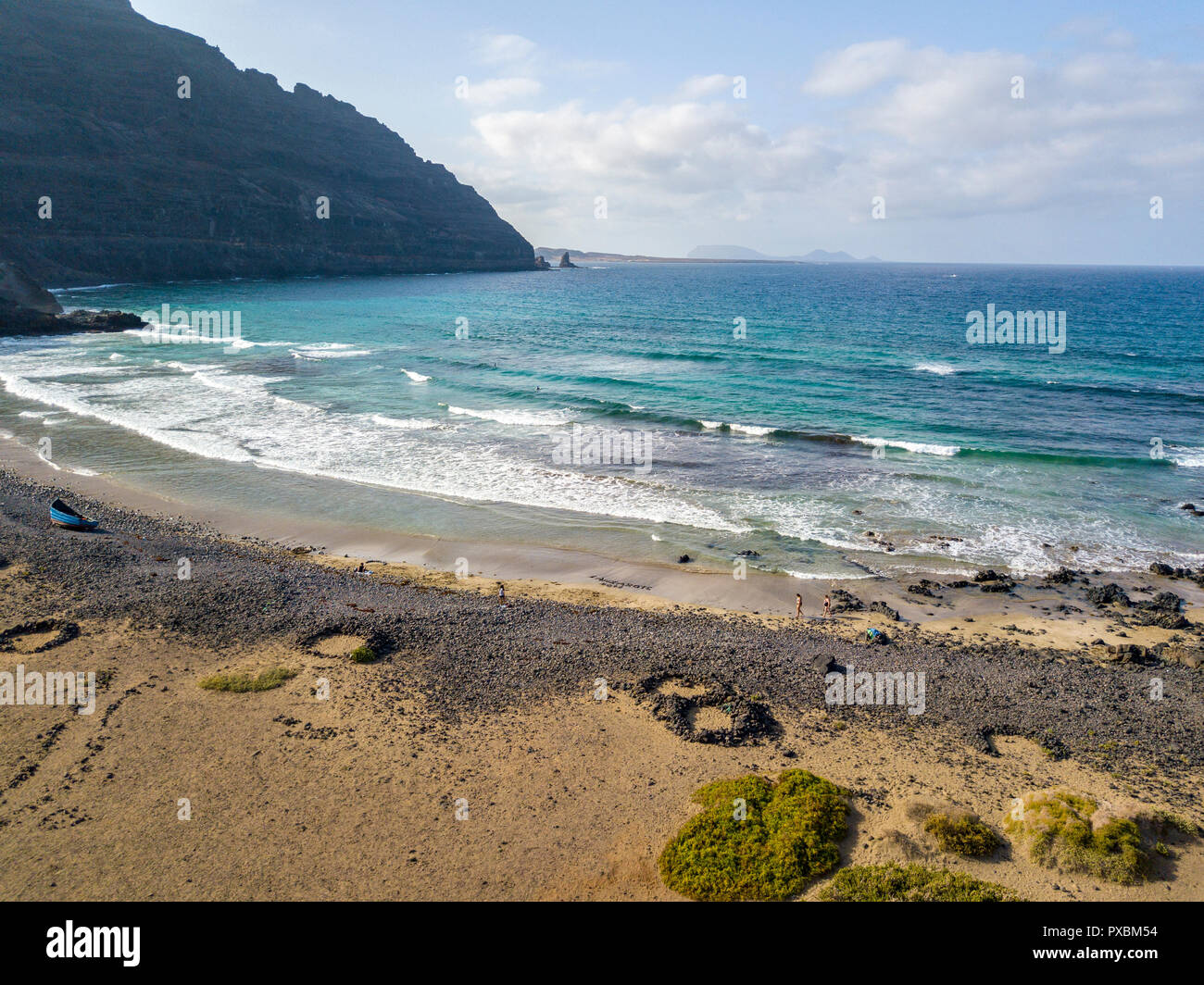 Aerial view of a crystal clear sea with waves and surfers. Playa De La Canteria.Waves crashing on the beach at sunset.Orzola, Lanzarote, Canary Island Stock Photo