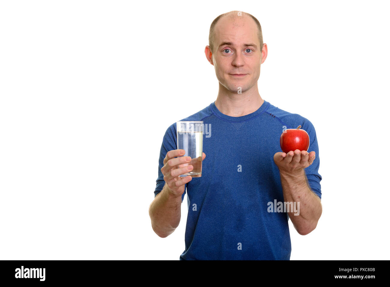 Bald Caucasian man holding glass of water and red apple Stock Photo