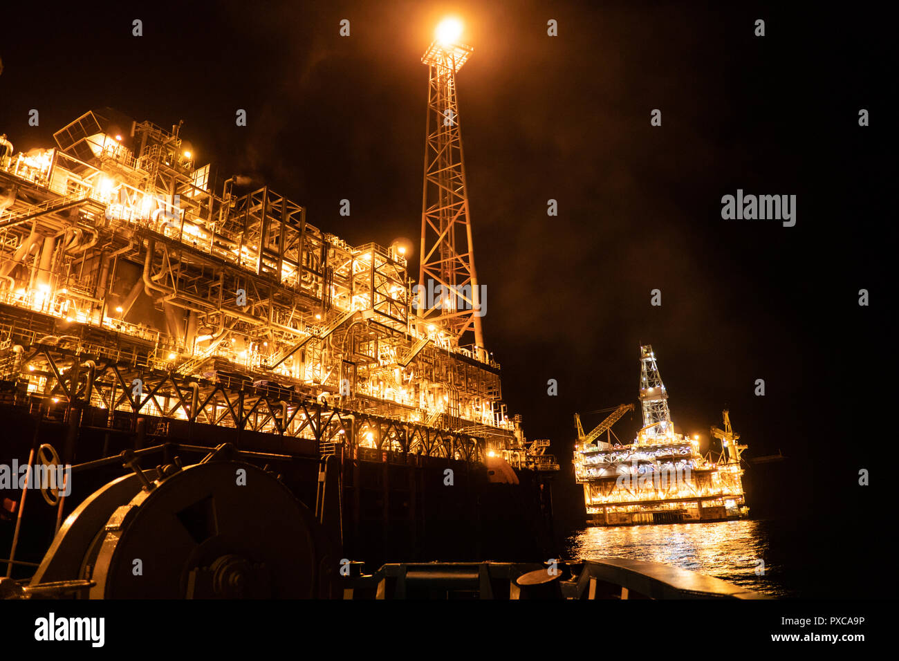 FPSO tanker vessel near Oil platform Rig at night. Offshore oil and gas industry Stock Photo