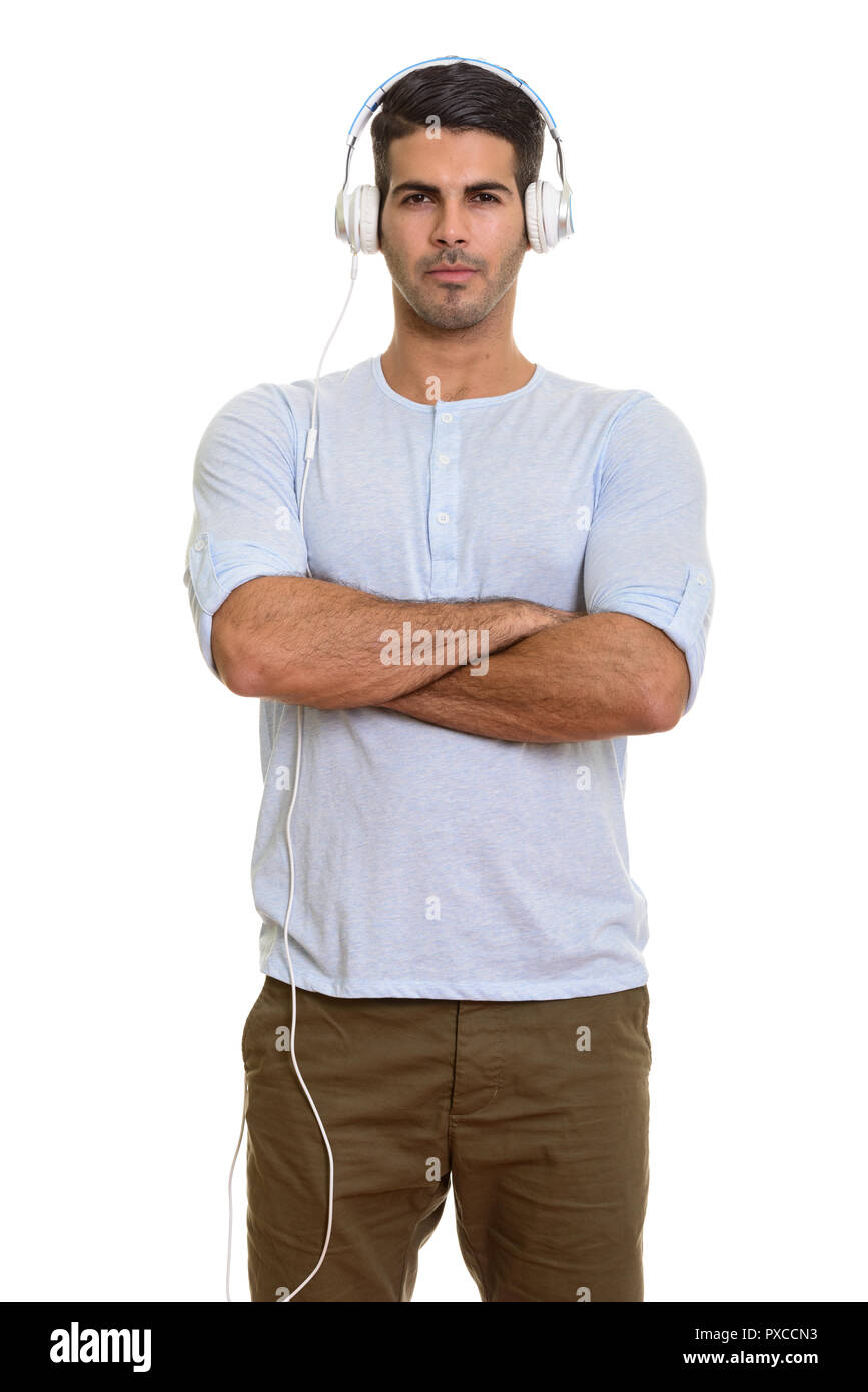Young handsome Persian man listening to music with arms crossed Stock Photo
