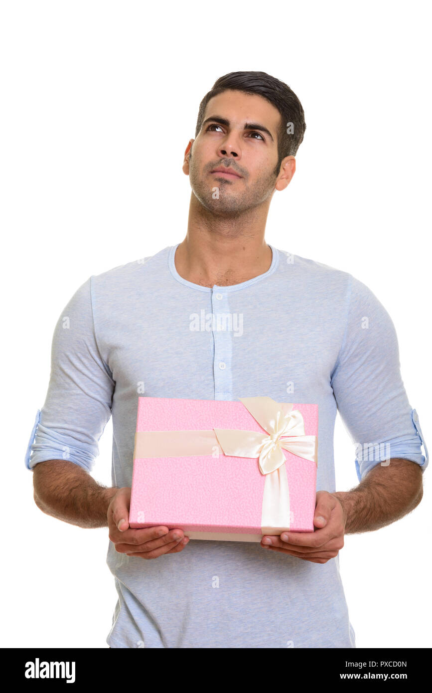 Young handsome Persian man holding gift box while thinking Stock Photo
