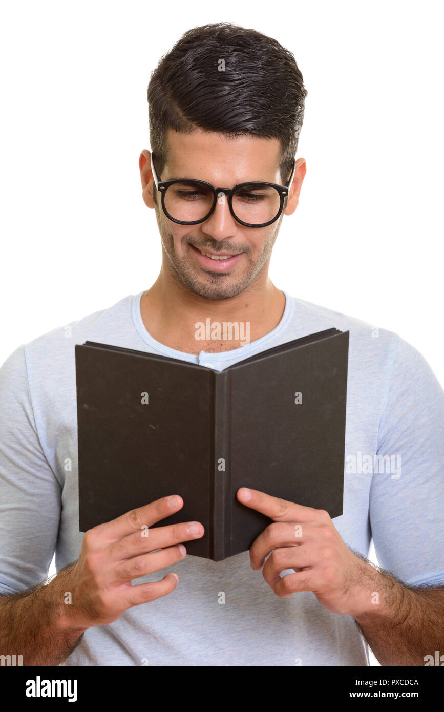Young happy Persian man smiling while reading book Stock Photo