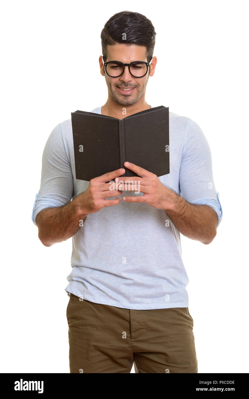 Young happy Persian man smiling while reading book Stock Photo