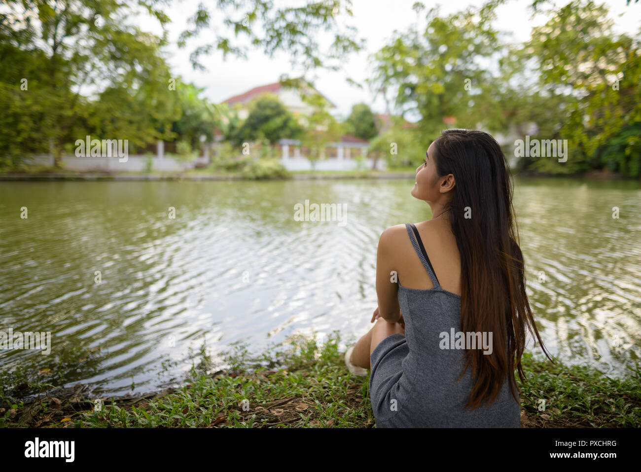 Young beautiful Asian woman relaxing by the lake at the park Stock Photo