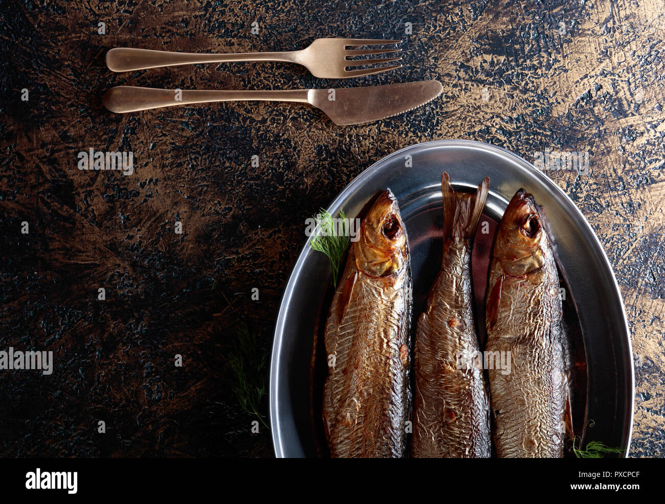 Smoked herring with dill on a metal dish. Copy space for your text