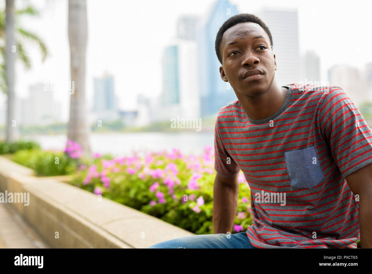 Young handsome African man relaxing at the park and thinking Stock Photo