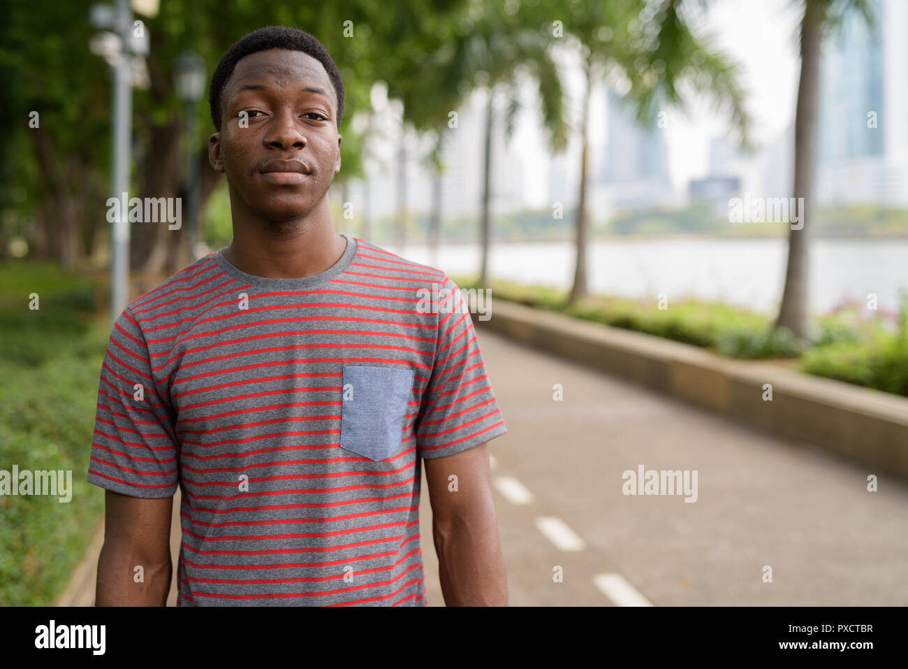 Portrait of young handsome African man relaxing at the park Stock Photo