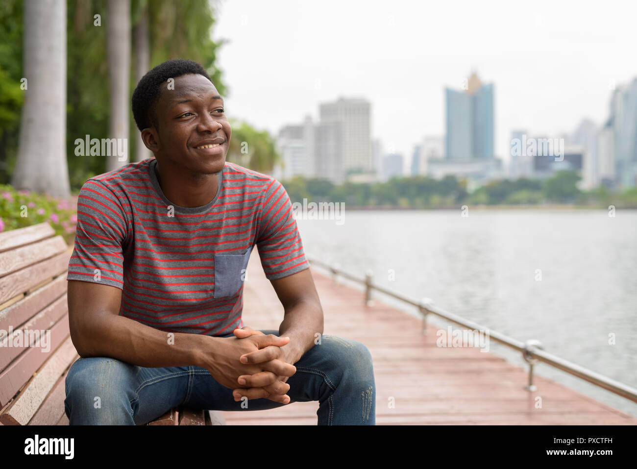 Young handsome African man relaxing and thinking at the park Stock Photo