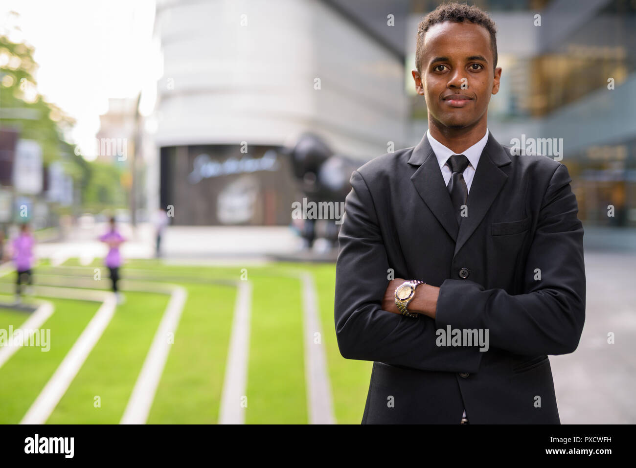 Portrait of successful young African businessman outdoors with arms ...