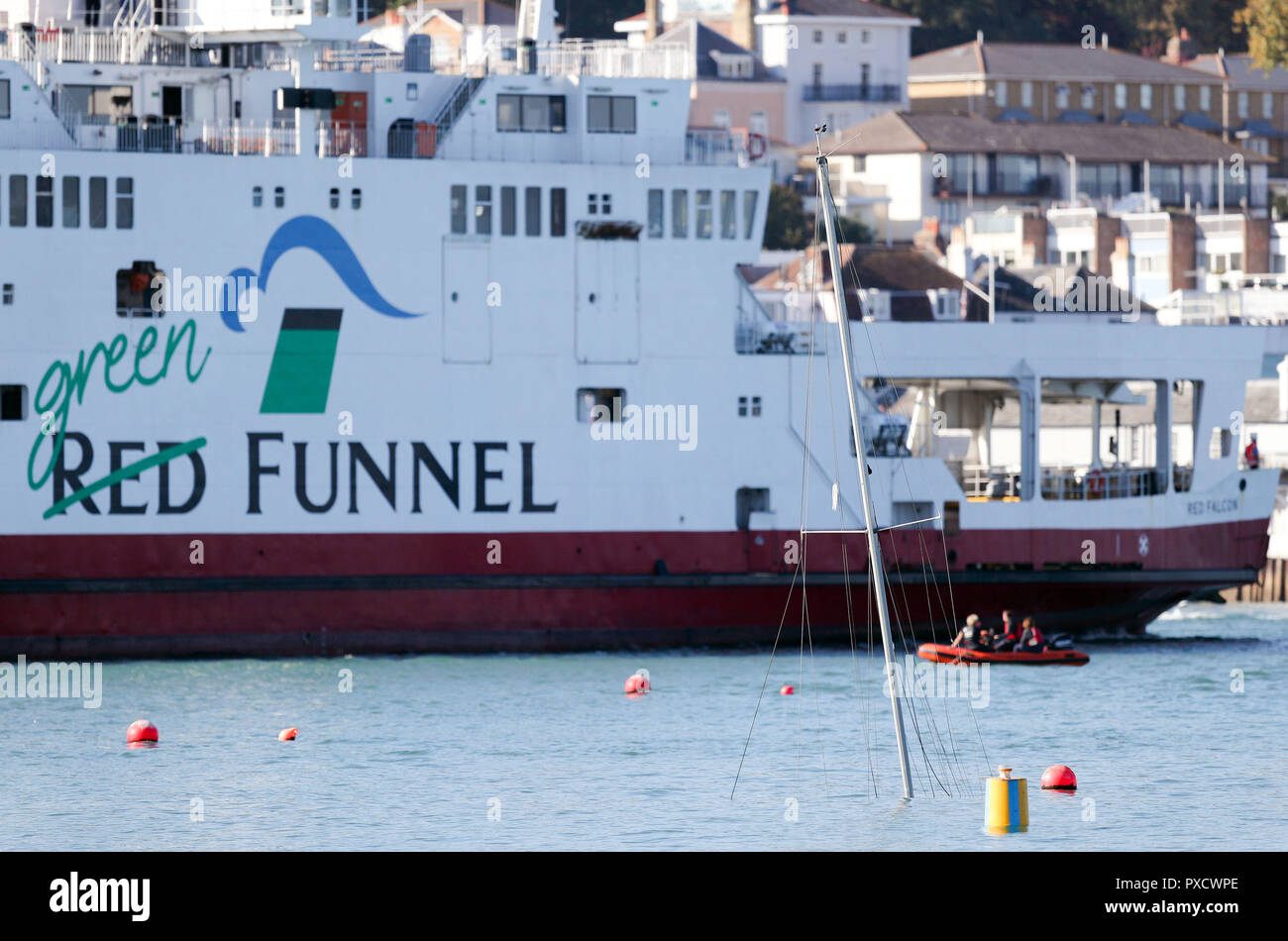 The Red Funnel car ferry, Red Falcon, which earlier collided with several small boats due to bad weather, passes the mast of a submerged yacht as she leaves East Cowes on the Isle of Wight bound for Southampton. Stock Photo