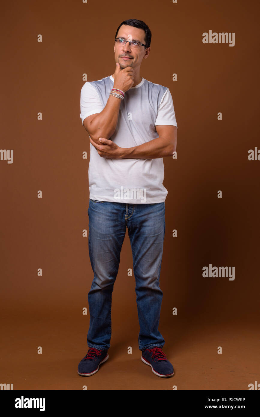 Full body shot of handsome man thinking against brown background Stock Photo