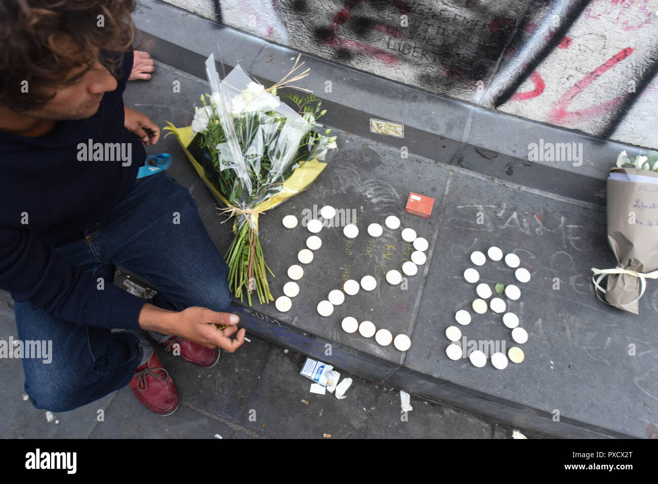 November 14, 2015 - Paris, France: Parisians gather on Place de la Republique to pay tribute to the victims of the deadly terrorist attacks. The number 128 refers to the number of people confirmed dead so far.  Des Parisiens se recueillent place de la Republique, au lendemain des tueries du 13 novembre 2015, dans lesquelles 130 personnes ont ete tuees par des terroristes djihadistes. Ce jeune homme a fait le nombre 128 avec des bougies, il s'agit du bilan au lendemain de l'attaque. *** FRANCE OUT / NO SALES TO FRENCH MEDIA *** Stock Photo