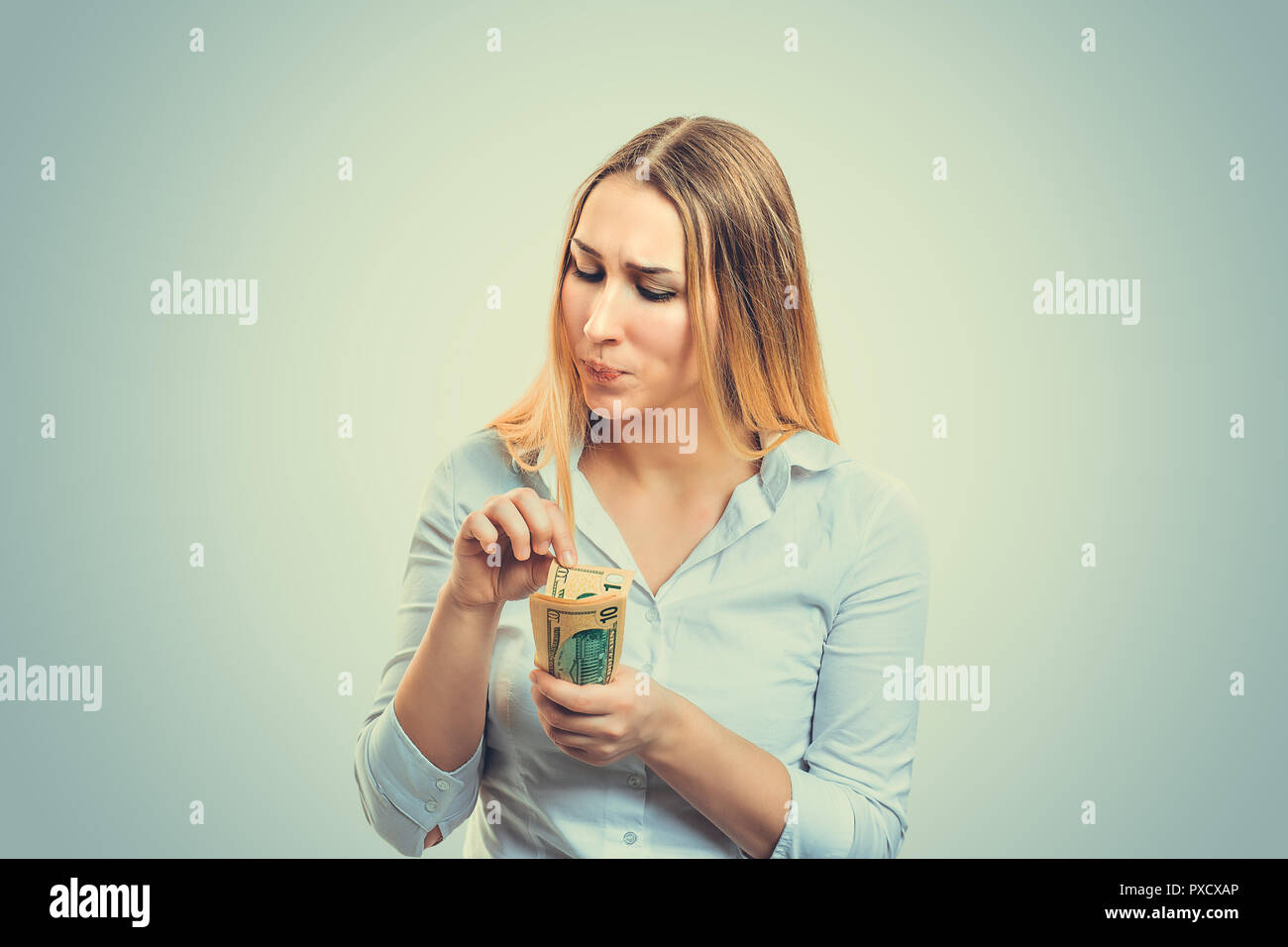 Young pedantic woman holding pile of money and counting bills Stock Photo