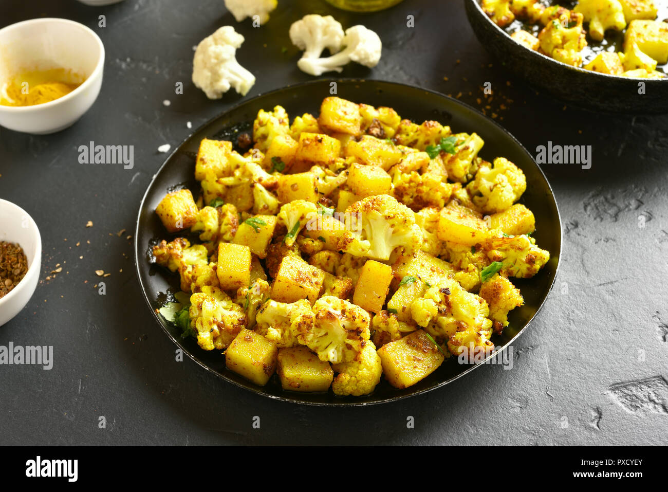 Tasty Aloo Gobi indian dish. Fried cauliflower with potatoes on black stone table Stock Photo
