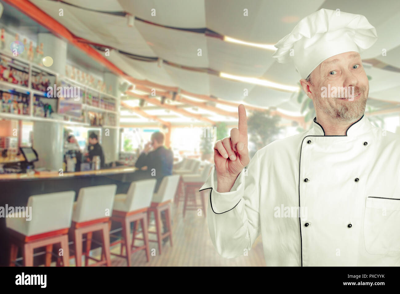 The chef is a white man in uniform with a bar counter. Stock Photo