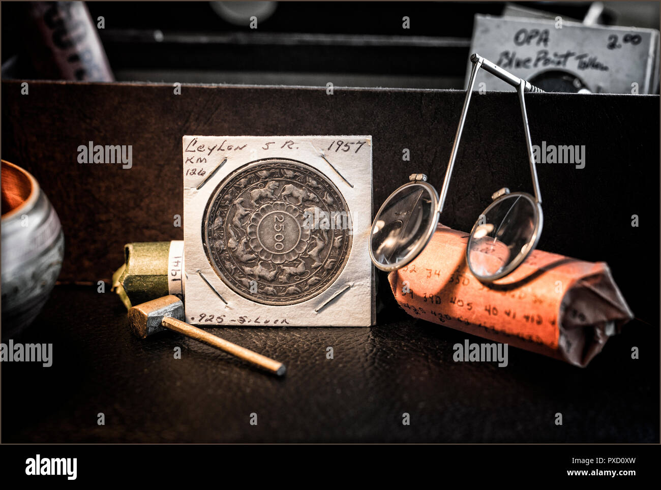 Coin Collector's Desk with rolled coins, magnifiers, Ceylon 2500 years of Buddhism Coin Stock Photo