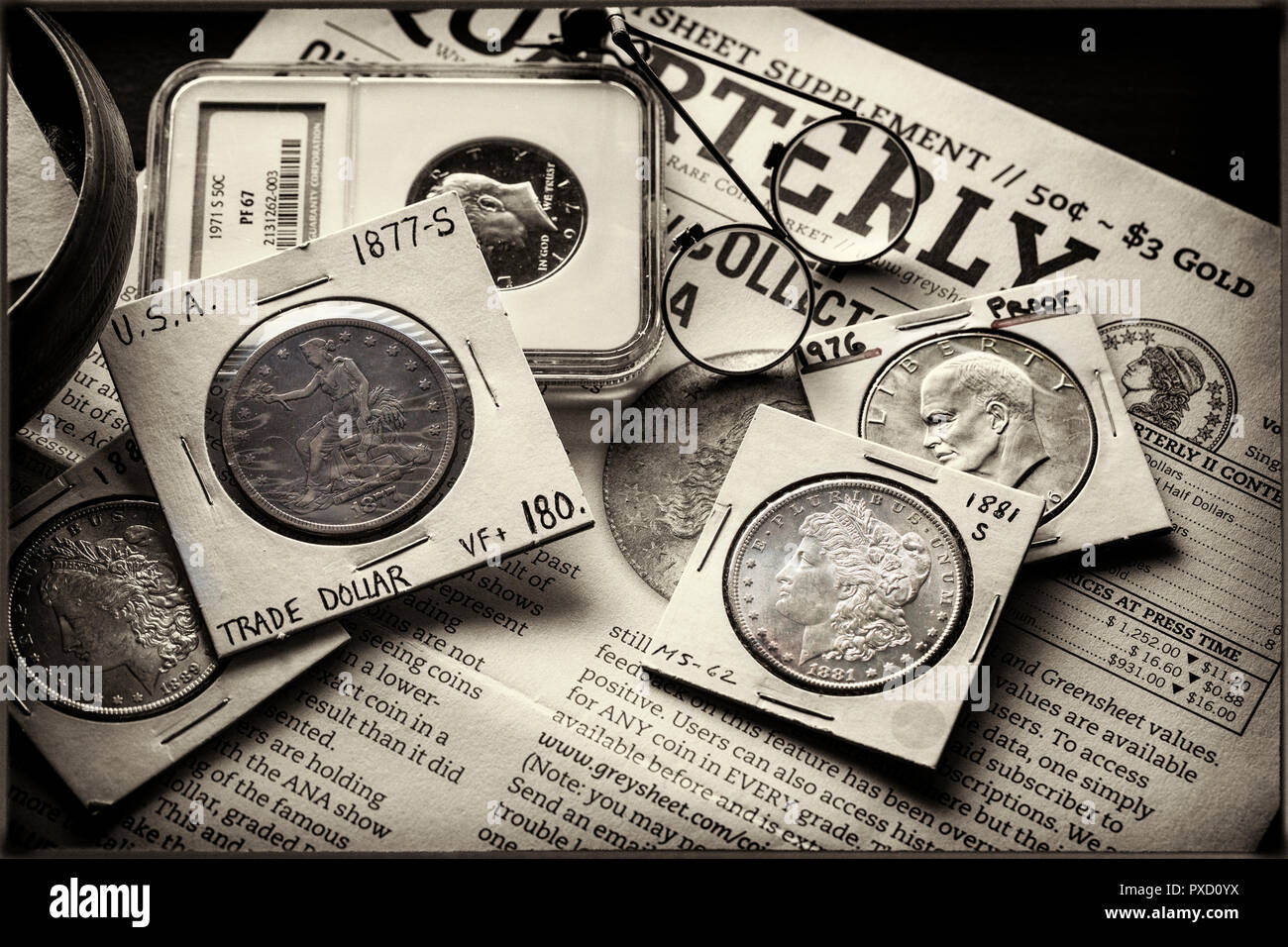 Coin Collecting - Various Coins - Morgan Dollars - Ike Dollar - Trade Dollar - against backdrop of the Greysheet with magnifiers Stock Photo