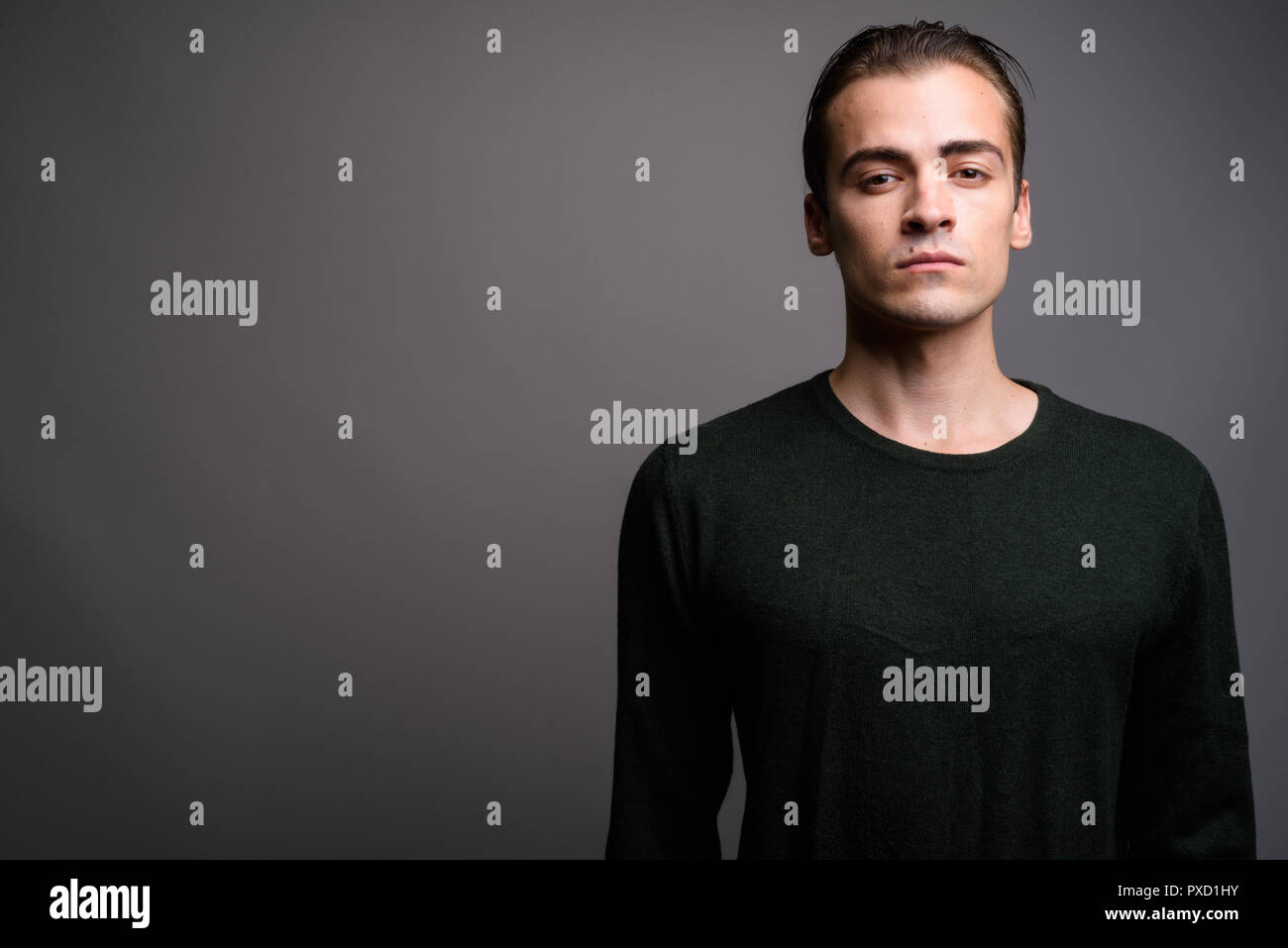Young handsome man wearing green long sleeved shirt against gray Stock Photo