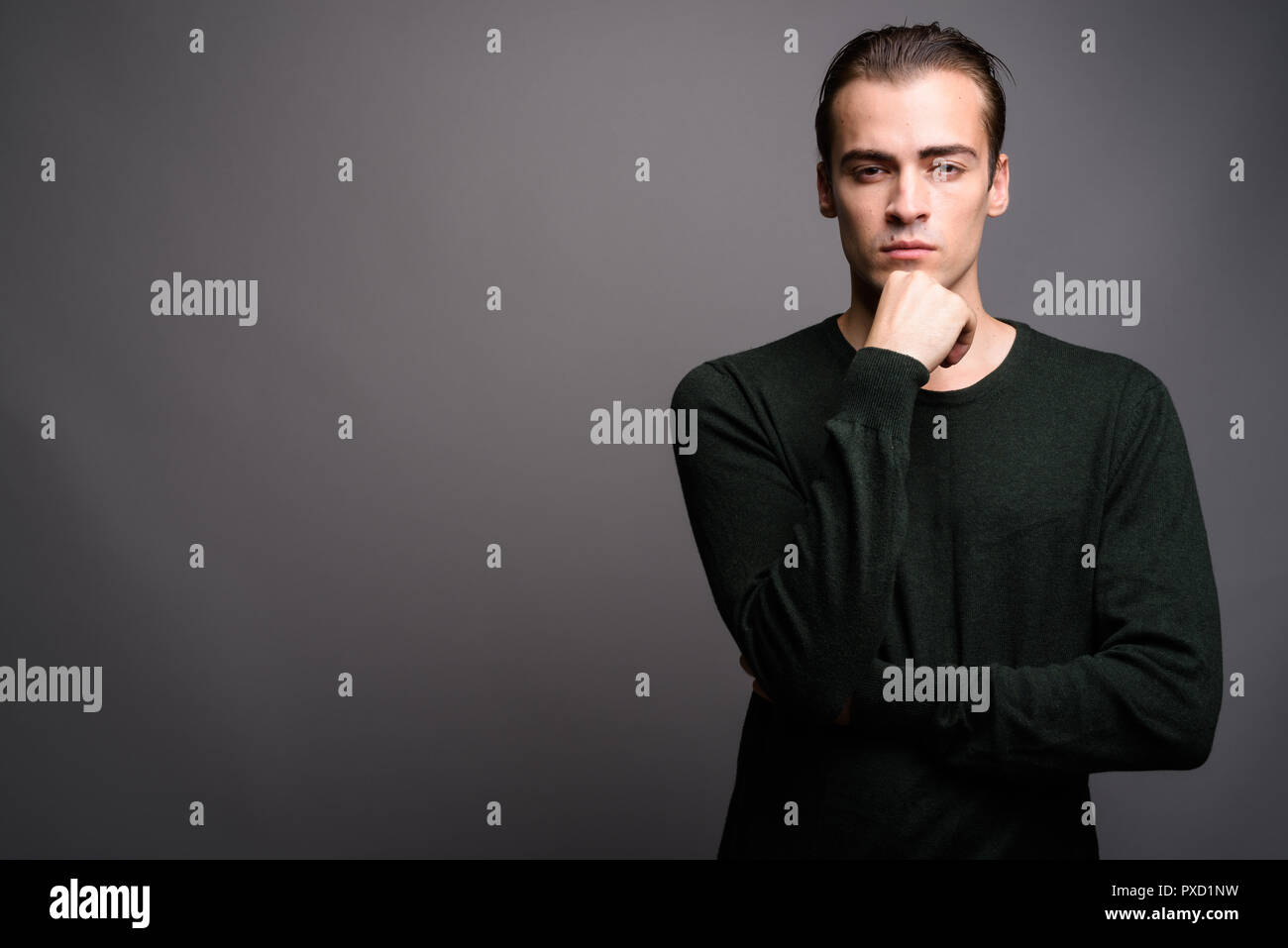 Young handsome man wearing green long sleeved shirt and thinking Stock Photo