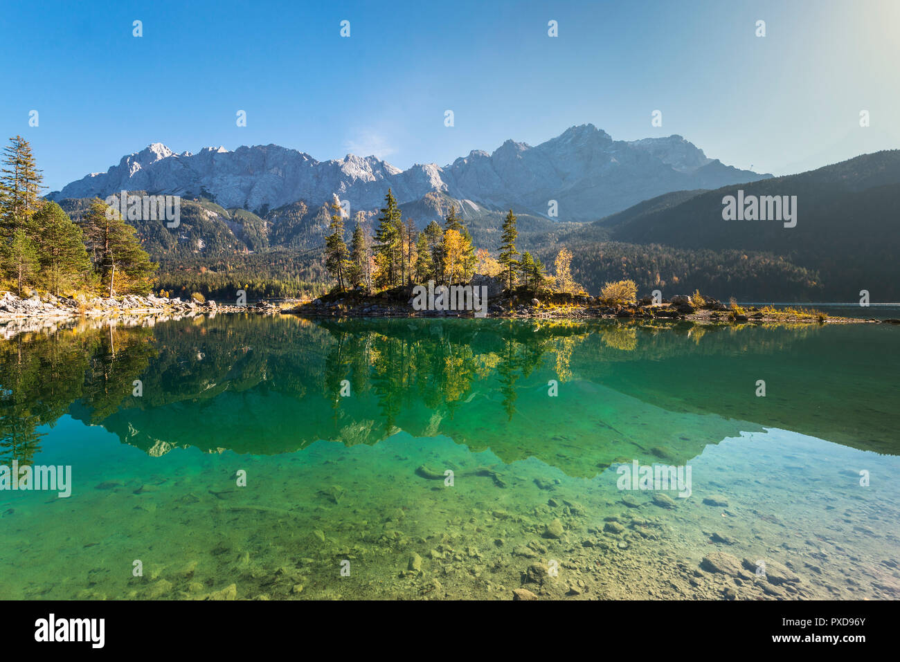 Autumn colored trees on the Braxeninsel in the Lake Eibsee in front of  the summit of Mount Zugspitze in the Wetterstein mountain range, Germany Stock Photo