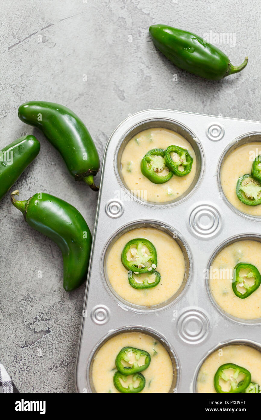 Flat lay. Cornbread batter in muffin pans garnished with jalapeno