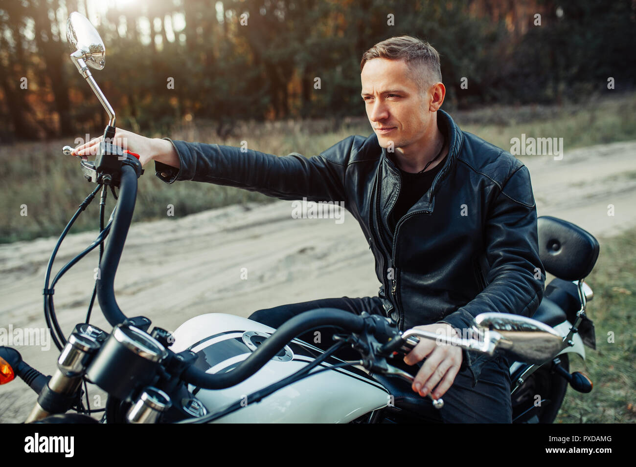 Handsome rider guy in black biker leather jacket on classic style cafe  racer motorcycle at sunset. Bike custom made in vintage garage. Brutal fun  urba Stock Photo - Alamy
