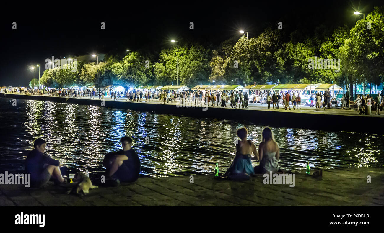 Night street market  in the old city of Zadar on the promenade with many tourists strolling, shopping, chilling and eating. Stock Photo