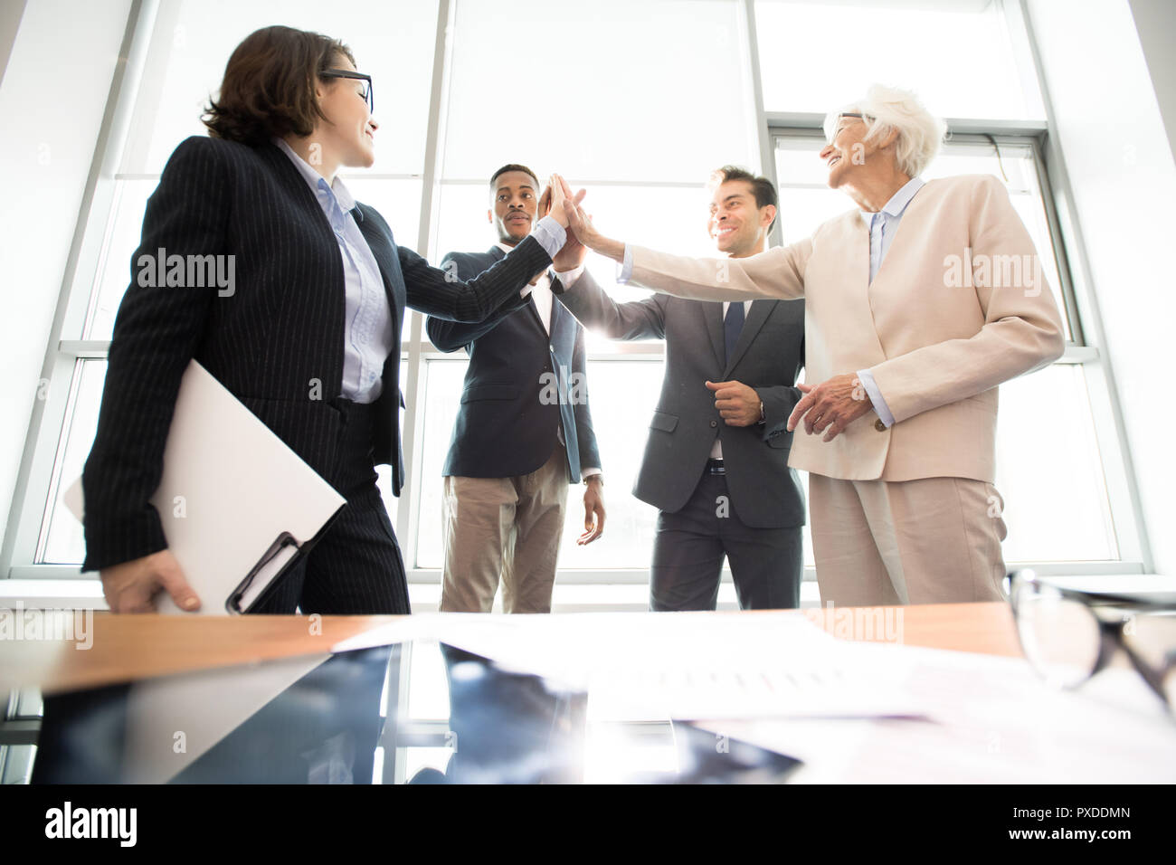 Successful business team giving high five in office Stock Photo - Alamy