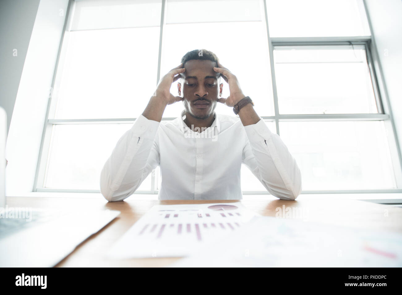 Puzzled African businessman analyzing graphs Stock Photo