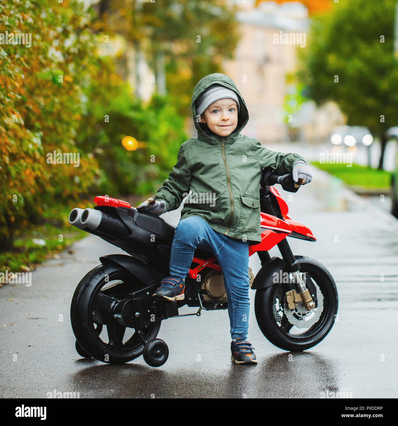 A beautiful little boy posing at his children's red motorcycle ...