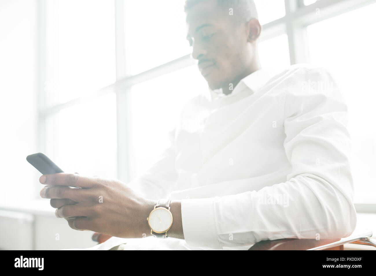 Carefree businessman using smartphone in office Stock Photo