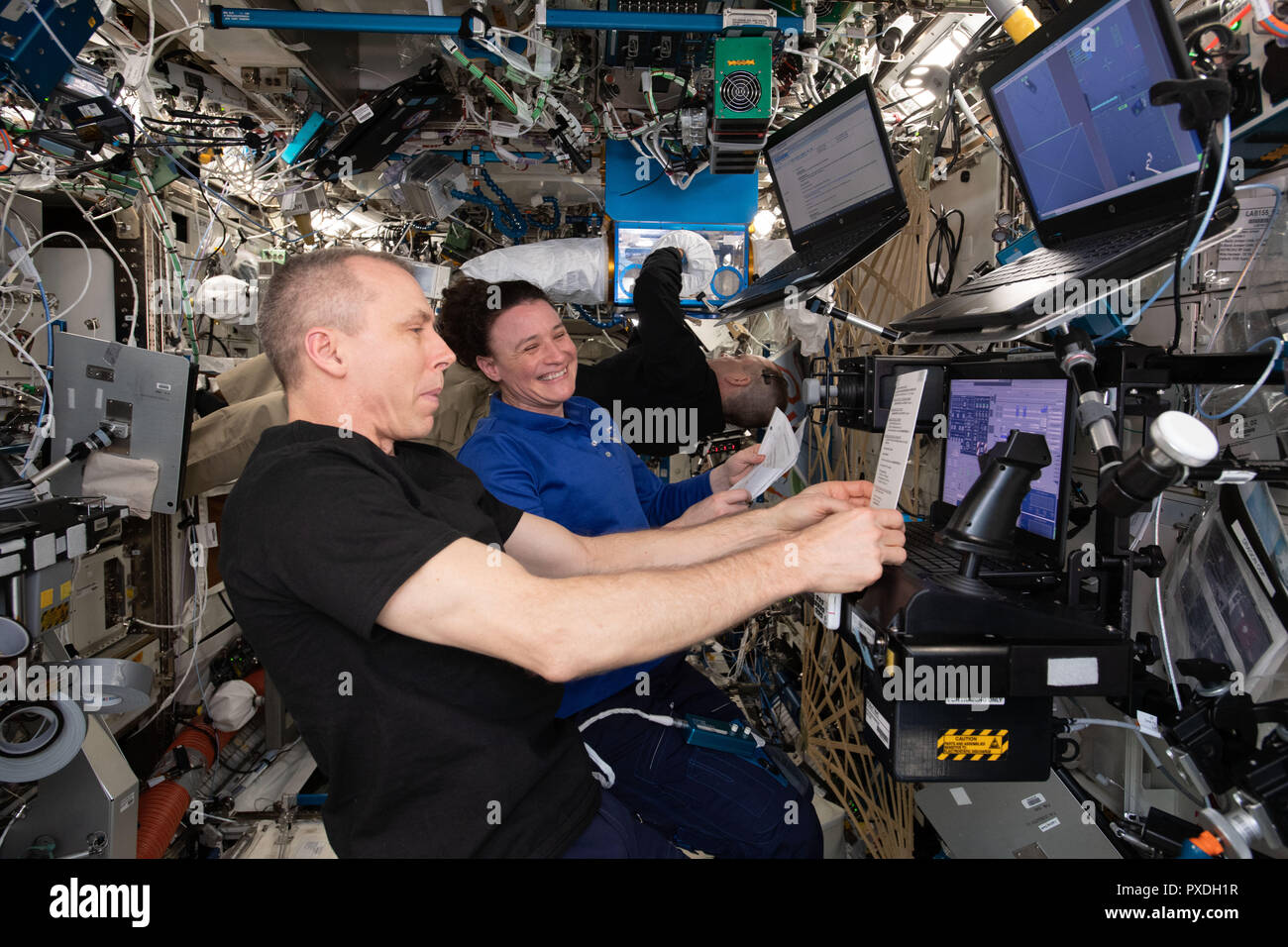 NASA astronauts Drew Feustel and Serena Aunon-Chancellor train on a computer in the U.S. Destiny laboratory practicing rendezvous procedures and robotics maneuvers ahead of the arrival of Japan's HTV-7 resupply ship September 6, 2018 in Earth Orbit. Stock Photo