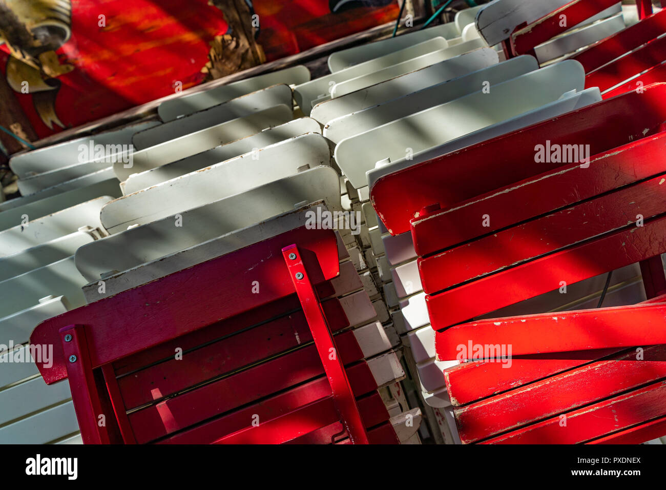Red and white painted, folded wooden chairs in front of a cafe in the Karolinenviertel in Hamburg, Germany. Stock Photo