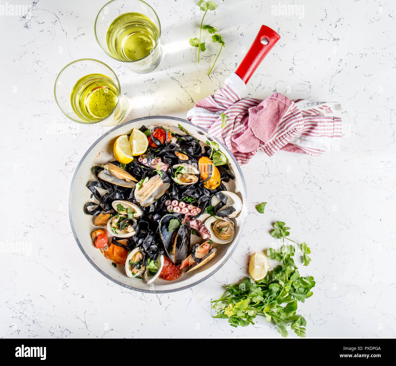 Homemade seafood Black pasta spaghetti with clams mussels octopus vongole in pan with white wine on marbled background Stock Photo