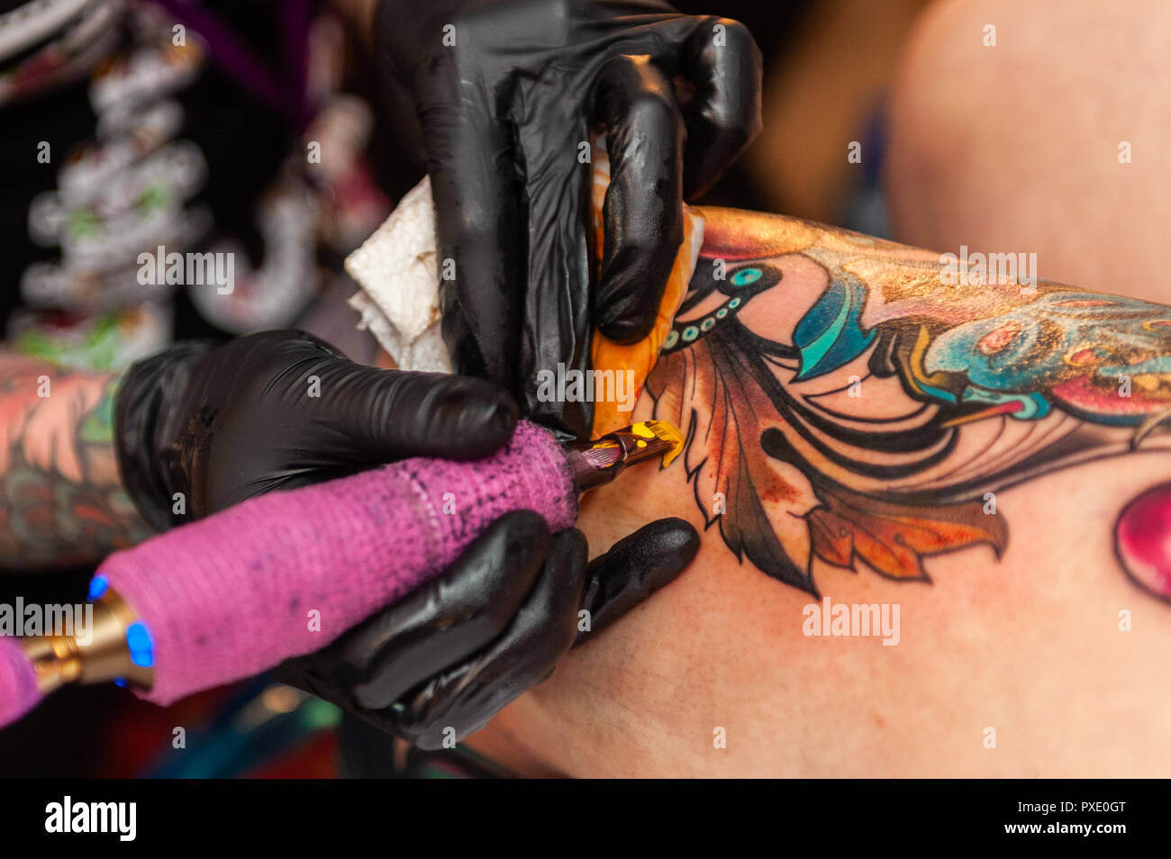 Skibbereen, West Cork, Ireland. 21st Oct, 2018. A tattooist tattoos the leg of a customer at the show.  The show has been attended by many tattooists from across Ireland, the North and the UK. Credit: Andy Gibson/Alamy Live News. Stock Photo