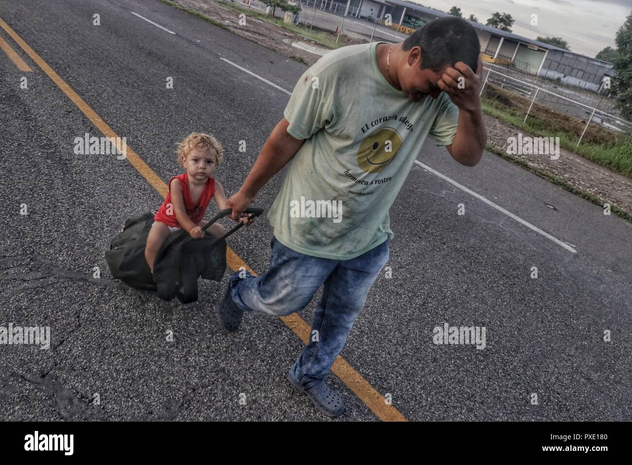 Ciudad Hidalgo, Mexico. 21st Oct, 2018. A Central American migrant marching with his child towards the United States. The migrants from Honduras, El Salvador and Guatemala have crossed the border fence between Guatemala and Mexico in order to march together from there to the US border. According to unofficial estimates there are about 4000 people. They're being escorted by the Mexican police. Credit: Iván Sánchez/dpa/Alamy Live News Stock Photo