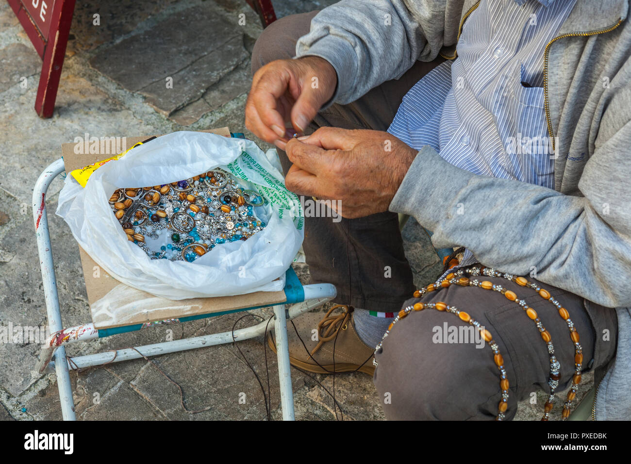 man handmade rosaries in a stree in Assisi. Perugia, Umbria, Italy Stock Photo