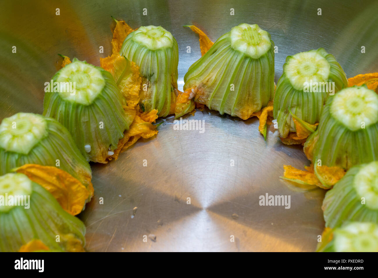 Cooking stuffed zucchini flowers / squash blossom - an Italian and Greek delicacy stuffed with rice, tomato, and herbs Stock Photo