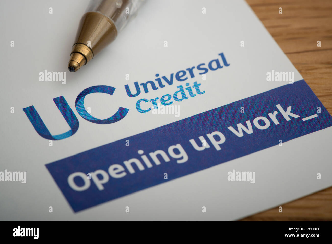 A piece of stationery featuring the Universal Credit logo, rests on a table along with a pen. Stock Photo