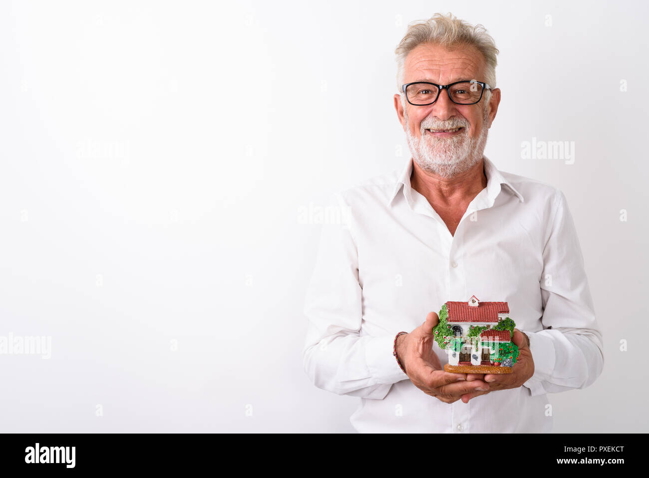 Studio shot of happy senior bearded man smiling while holding ho Stock Photo