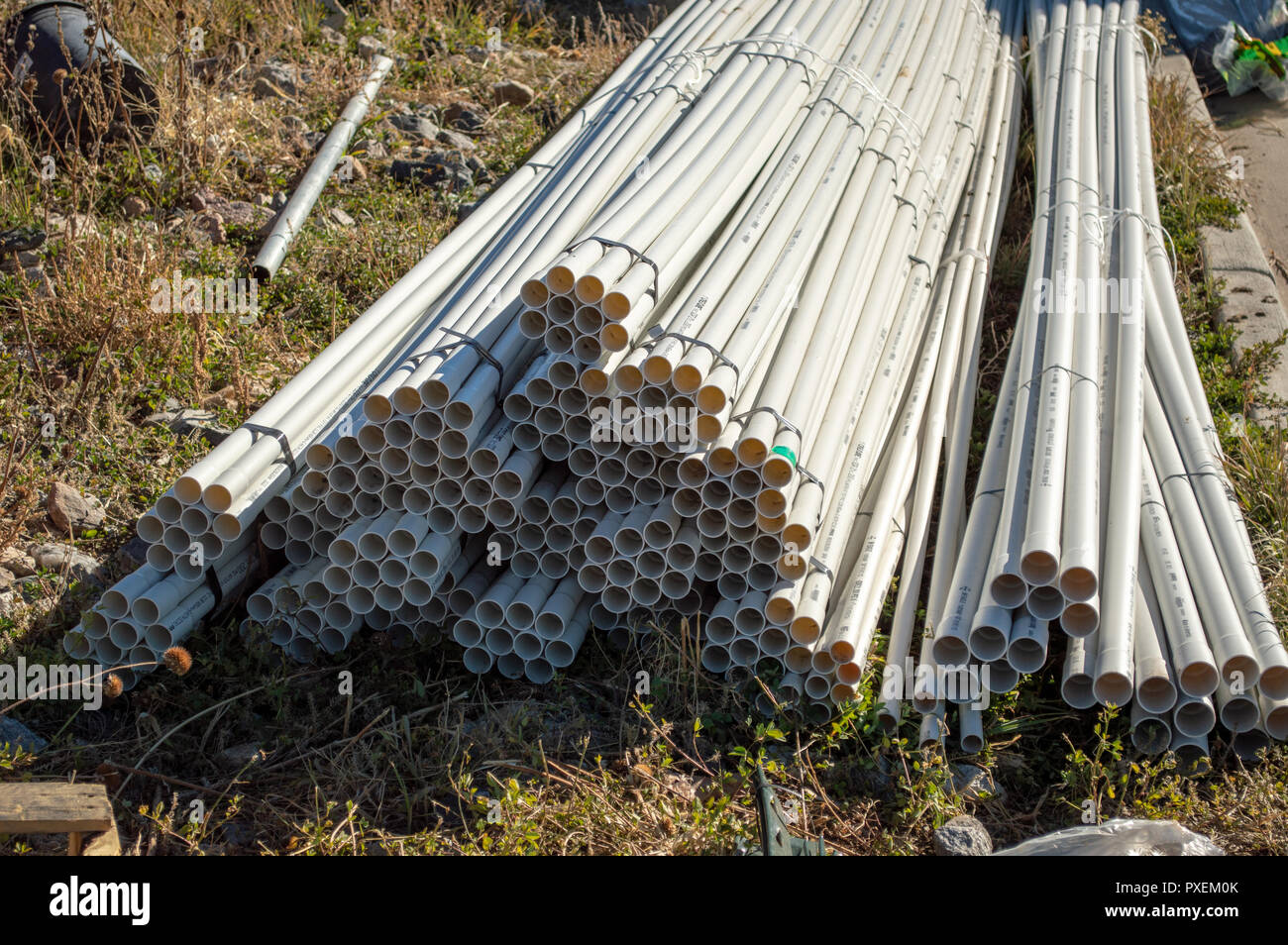 Piles of white PVC piping ready to be used at construction site Stock Photo