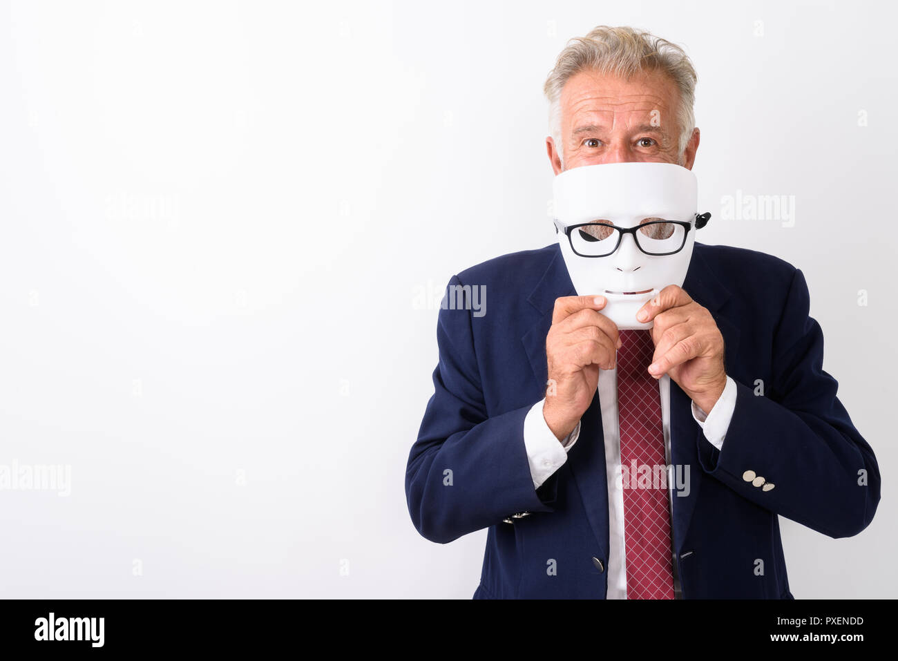 Studio shot of handsome senior bearded businessman hiding behind Stock Photo