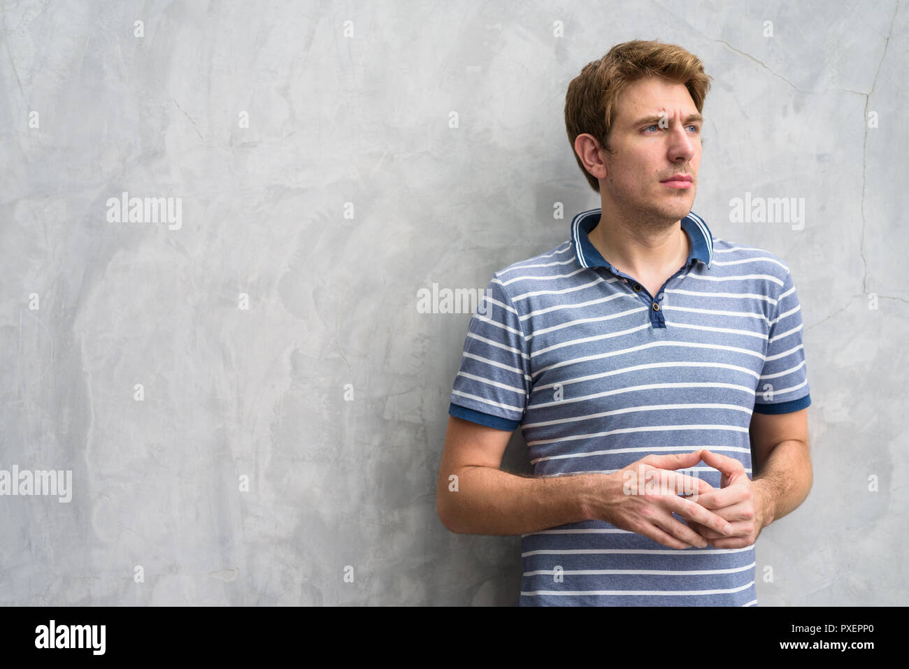 Portrait of handsome man with blond hair against concrete wall outdoors Stock Photo